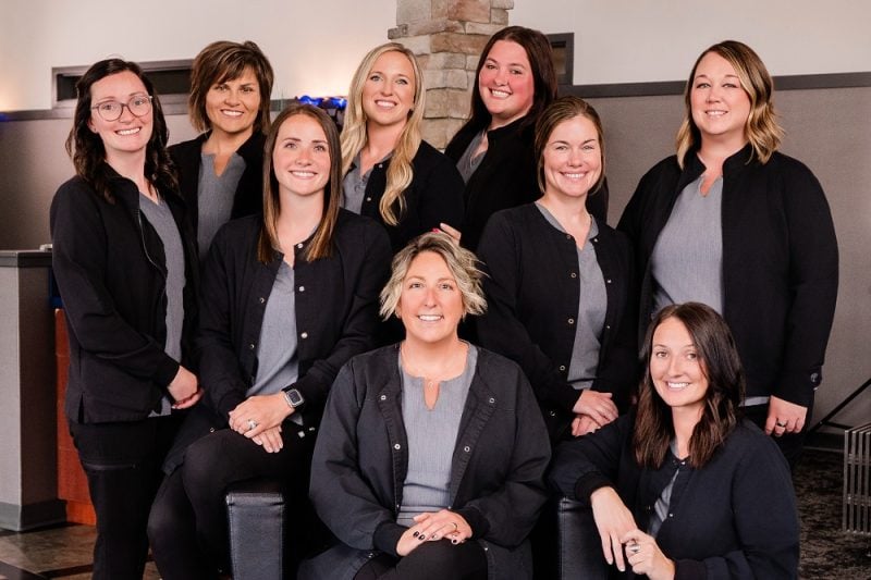 Professional group photo of dental office staff wearing black uniforms
