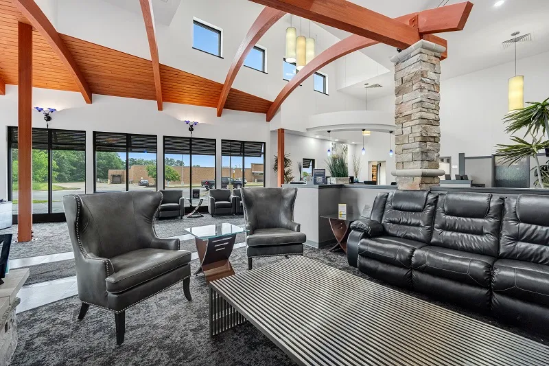 Modern dental office waiting area with exposed wood beams, black leather furniture, and stone fireplace