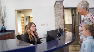 Receptionist at front desk assisting grandmother and child at dental office