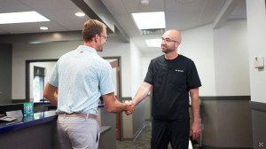 Dental professional shaking hands with colleague in office hallway